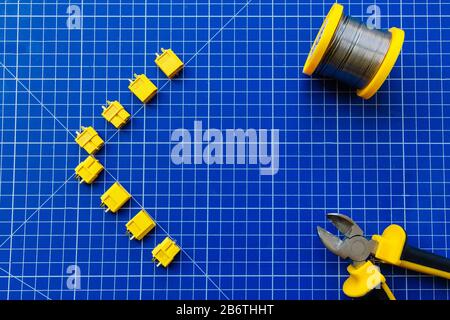 Blue rug for cutting. The connectors XT-60 are laid out on the mat. In one corner lies a solder coil. In another corner are yellow-black nippers. Pres Stock Photo