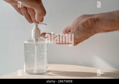 Man using hand sanitizer alcohol gel rub for hands hygiene at home or public space, hospital clinic for preventive coronavirus spread epidemic prevention. Stock Photo
