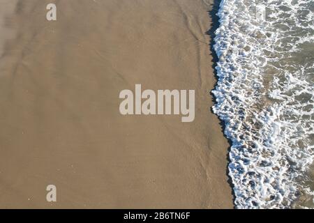 Waves reaching sandy beach, photo from above Stock Photo