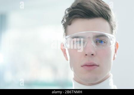 Portrait of serious handsome young man with hairstyle using smart digital goggles Stock Photo