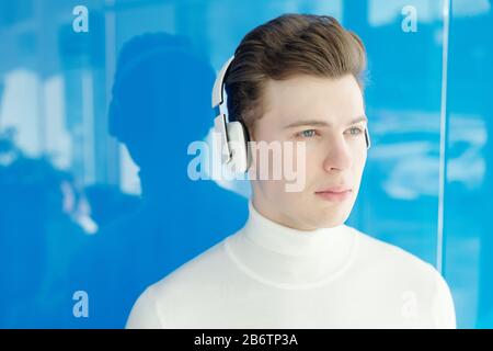 Serious pensive guy in modern wireless headphones looking into distance Stock Photo