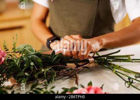 Hands of a female florist placing the stalks of a bouquet of flowers Stock Photo
