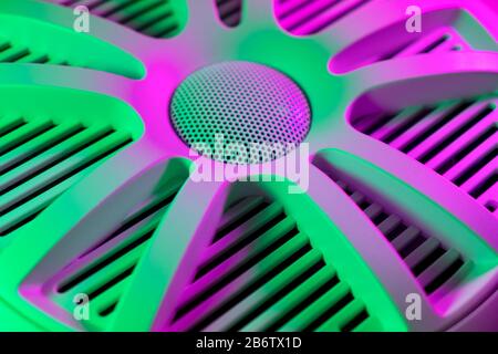 Colorful lights of car stereo and car speakers background.  Car music audio speaker in green and pink tones. Modern car audio system close up Stock Photo