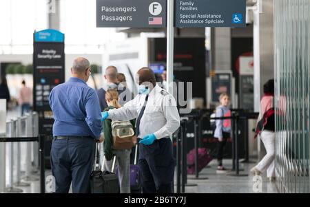 Toronto, Canada. 11th Mar, 2020. A staff member (C) of the Canadian Air Transport Security Authority (CATSA) on duty with face mask and gloves is seen at the Terminal 1 of the Pearson International Airport in Toronto, Canada, March 11, 2020. At least 93 confirmed COVID-19 cases and one death have been reported in Canada so far. Credit: Zou Zheng/Xinhua/Alamy Live News Stock Photo