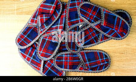 A lot of colorful comfortable, cushioned, checkered disposable slippers are on the wooden floor. Top view. Concept of hospitality. Close-up. Indoors. Stock Photo