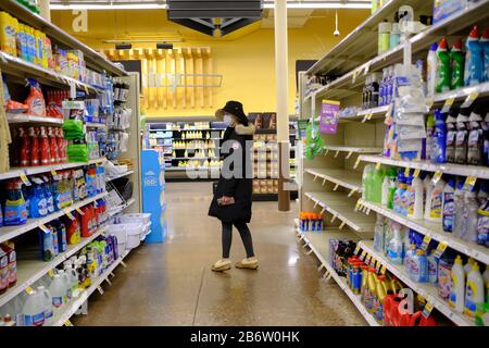 03112020 - Bloomington, Indiana, USA: A woman wearing a mask shops for cleaning supplies at a Kroger in Bloomington, Ind., where shoppers were stocking up on toilet paper, and other items on the day World Health Organization declared Coronavirus to be a pandemic. Toilet paper, wipes, protective breathing masks, and other items are either sold out at local stores, or are in short supply. Stock Photo