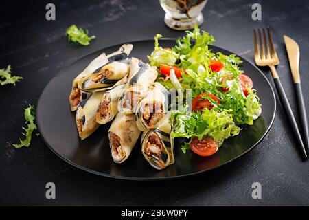 Pancake week. Shrovetide. Rolled pancakes stuffed chicken meat and vegetables. Savory crepes. Stock Photo