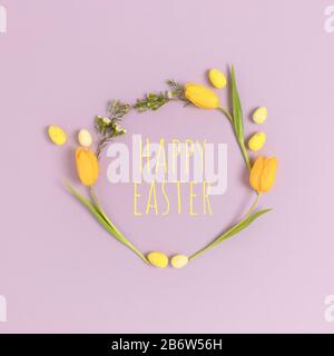 Wreath made of eggs and flowers on a purple pastel background. Quote Happy Easter. Holiday concept. Stock Photo