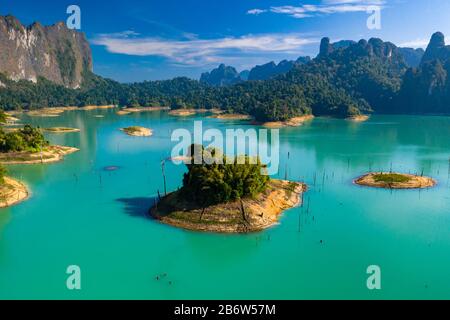 Aerial drone view looking down onto tiny, jungle covered islands in a huge lake surrounded by limestone cliffs. (Cheow Lan Lake, Khao Sok) Stock Photo
