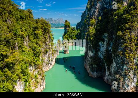 Aerial drone view of longtail boats around spectacular limestone fingers and karsts on a huge lake surrounded by jungle Stock Photo