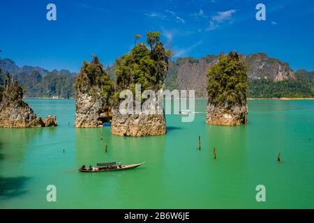 Aerial drone view of longtail boats around spectacular limestone fingers and karsts on a huge lake surrounded by jungle Stock Photo