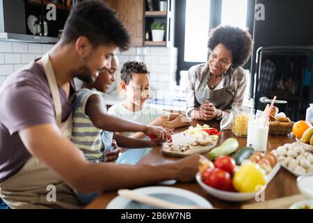 Happy family in the kitchen having fun and cooking together. Healthy food at home. Stock Photo