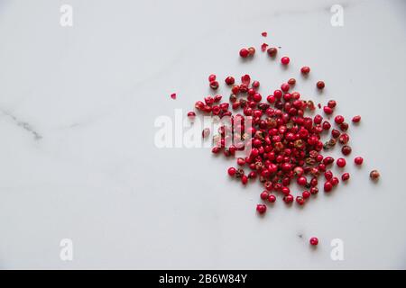 Pink pepper in spoon on stone background. Spice closeup top view Stock Photo