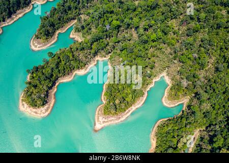 Aerial view looking downwards onto tiny islands and fingers of tropical rainforest covered land in a huge lake Stock Photo