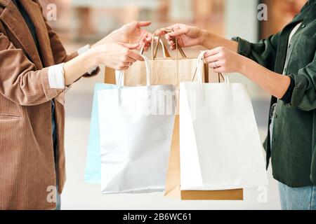 Seller giving paper bags of packed goods to woman and thanking her for shopping Stock Photo