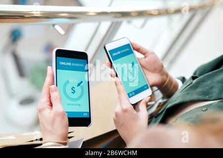 Close-up of unrecognizable women using mobile phones while transferring money online Stock Photo