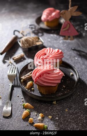Cupcakes with fruit flavor cream.Easter dessert.Wooden bunny on the table.Delicious food. Stock Photo
