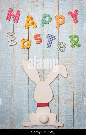 Easter composition with with Easter bunny and text happy Easter on light blue wooden background. Top view with copy space. Stock Photo
