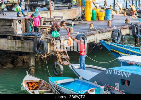 Local people loading up their small boat with shopping supplies to take to a nearby island where they live, Sandakan, Sabah district, Borneo, Malaysia Stock Photo