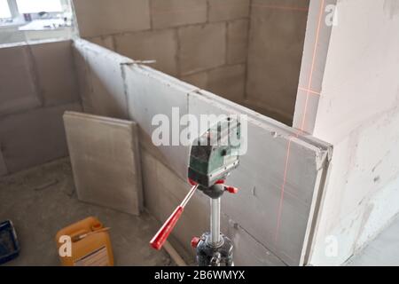 The construction worker Measures horizon level with a laser level. Construction of internal walls in the apartment using a plaster concrete plate with Stock Photo