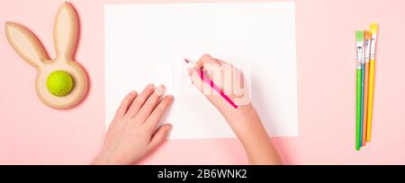 Banner Kids hand holding paintbrush on blank page, top view. Mother's day Easter concept. Handmade postcard. Love care Stock Photo
