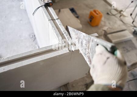 Saw in hand saws Gypsum plate. Construction of internal walls in the apartment using a plaster concrete plate with groove ridge. New building without Stock Photo