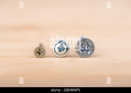 Slots of metal screws. Metal screws on a wooden background. Copy space. Close up Stock Photo
