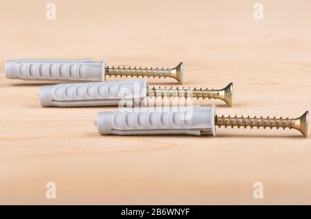Metal screws and plastic dowels on a wooden background. Close up. Copy space. Stock Photo