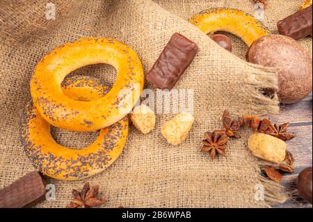 Bagels, chocolate, pieces of brown sugar and star anise on a background of rough fabric. Close up Stock Photo