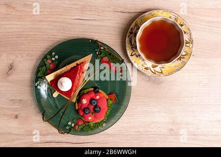 Two appetizing delicious red cakes on a glass plate with cup of tea nearby, top view Stock Photo