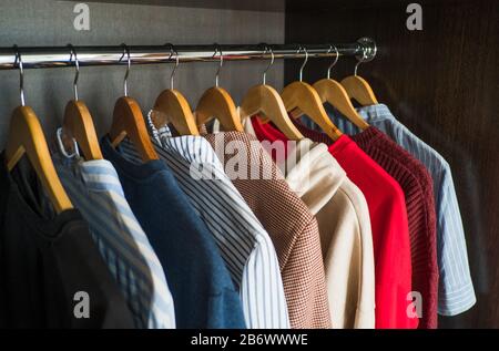 Hangers with different clothes in wardrobe closet. Stock Photo