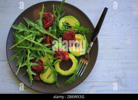 Healthy fitness salad with arugula, avocado, feta and yellow cherry tomatoes. Recipe for salad with avocado, arugula and white cheese. Vegetarian nutr Stock Photo