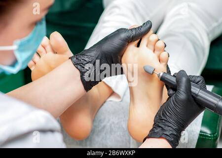 Process of polishing foot of woman close up with special machine tool.