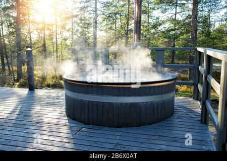 Modern big barrel outdoor hot tub in the middle of forest. The hot tub's soothing warm water relaxes muscles and eases tensions, so your worries can s Stock Photo
