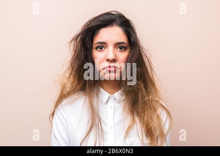 sad woman with tangled hairs in white shirt against pink background. morning woman's routine Stock Photo