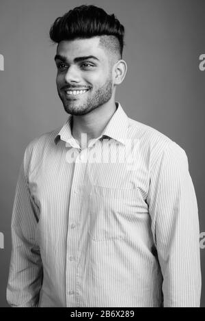 Young handsome Indian businessman against gray background Stock Photo