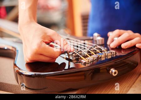 Hand of guitar maker works on electric guitar with an Allen key Stock Photo