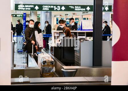 Milan Malpensa Airport, Italy. 12th Mar, 2020. Passengers wearing protective face masks in the empty departures terminal of Malpensa (MXP) airport. US President Trump suspended travel from Europe (except UK) for 30 days amid Coronavirus outbreak fears. Credit: Piero Cruciatti/Alamy Live News Stock Photo