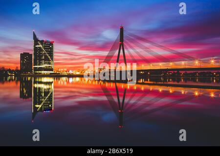 Sunset on the Daugava River in Riga against the background of skyscrapers and cable-stayed bridge Stock Photo