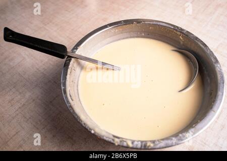 Pancake dough in a bowl on the table, next to the soup ladle. Top view. Stock Photo
