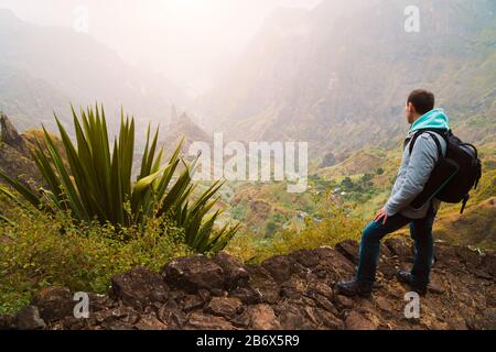 Active vacation at Santo Antao Island, Cape Verde. Traveler with backpack on hike enjoying view of surreal Xo Xo valley and mountain ridge. Stock Photo