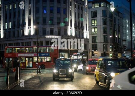 LONDON, UK- febryary 15 2020: London nightlife. Reflections on wet pavement from taxis and buses. Center Stock Photo