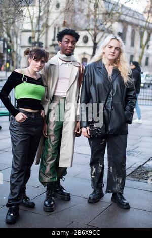 LONDON, UK- febryary 15 2020: Fashionable people on the street . Street style. A man in a long beige cloak, a neckerchief and green iridescent trouser Stock Photo