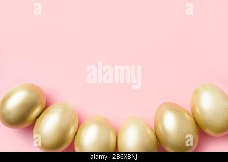 Golden eggs as border on pastel pink. Happy Easter background. Greeting card. Top view with copy space. Stock Photo