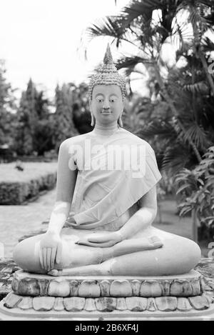 Sculpture of Buddha wearing yellow robe while meditating Stock Photo