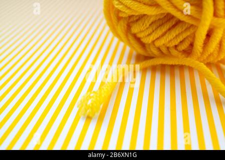 Yellow yarn ball on a yellow striped background. Stock Photo