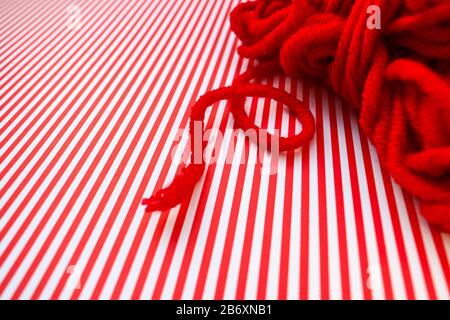 Red yarn ball on a red striped background. Stock Photo
