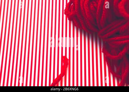 Red yarn ball on a red striped background. Stock Photo
