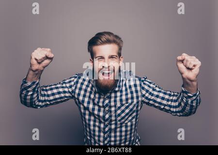 Excited happy young bearded man triumphing with raised hands Stock Photo