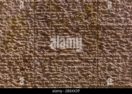Wall covering made of natural stone grooved and broken in reddish pastel color Stock Photo